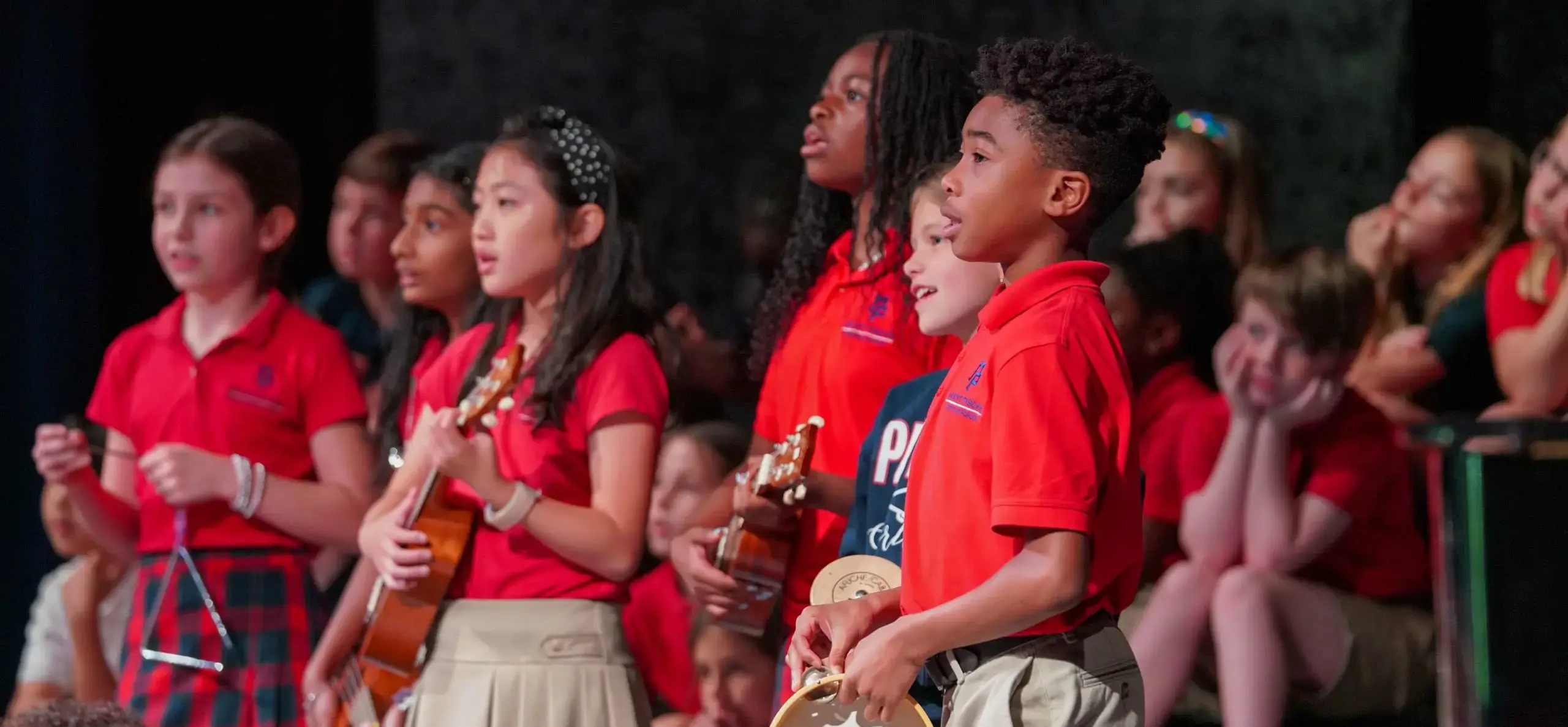 Students stand on a stage and play instruments