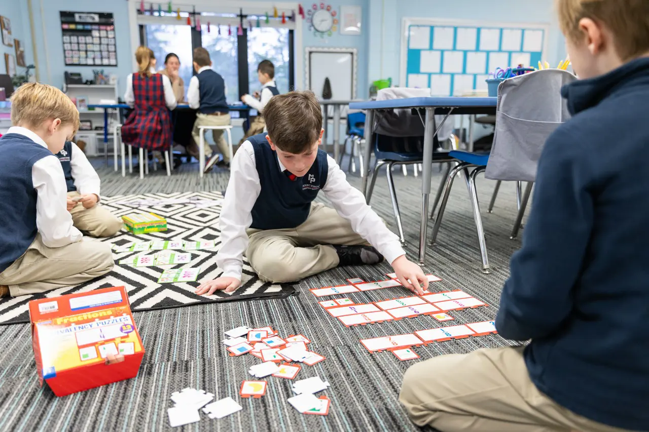Lower School students working fraction puzzles on the classroom floor