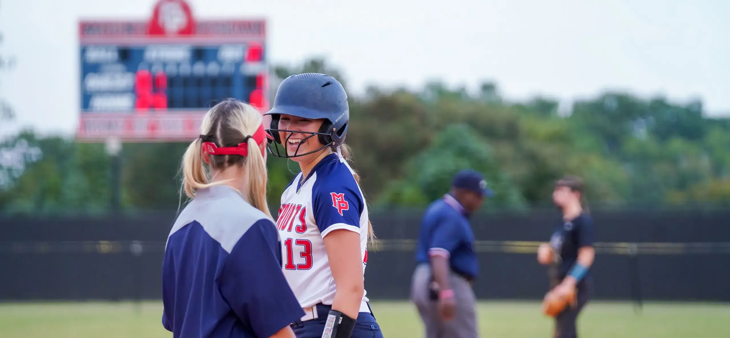 Softball player talks to coach on the field