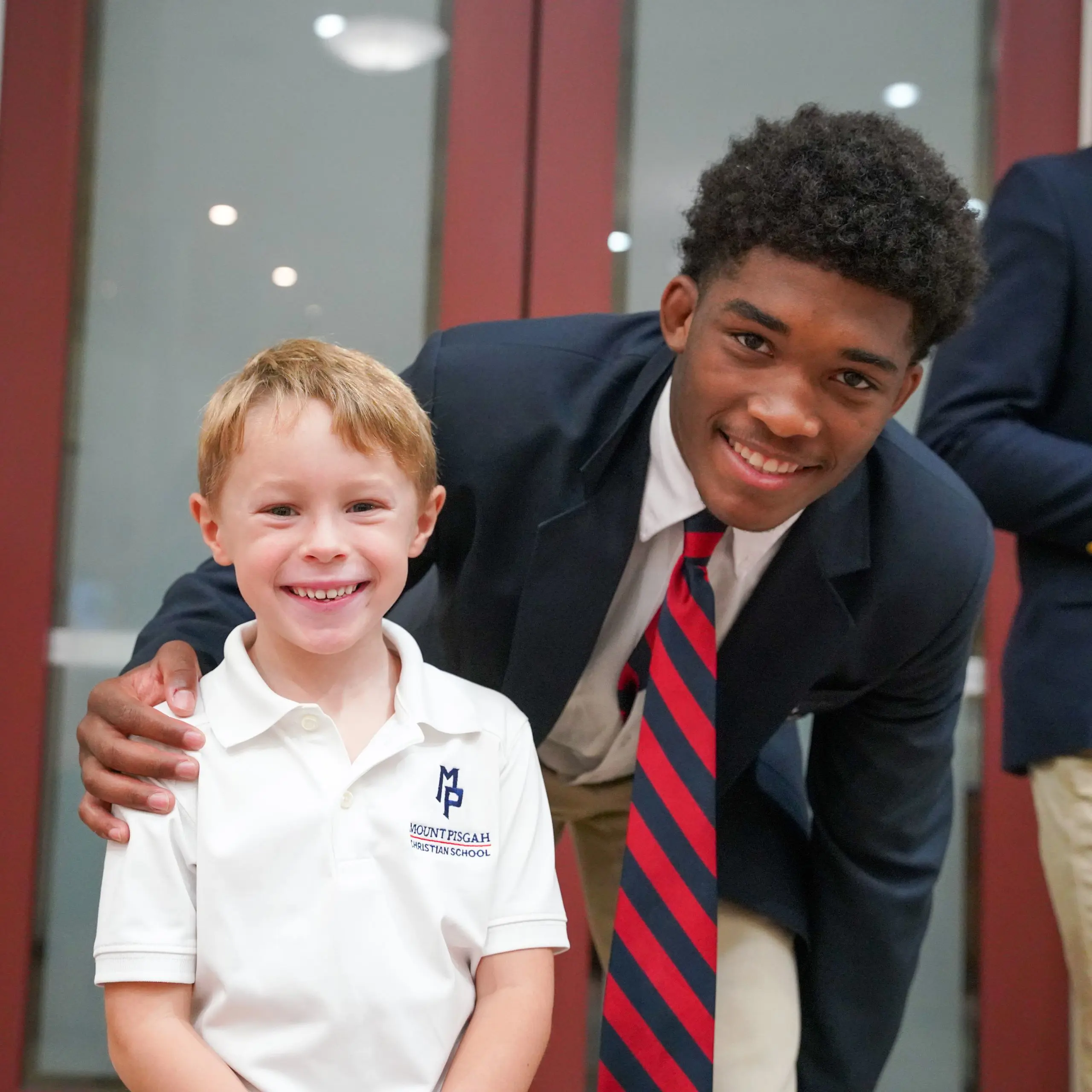 A senior and kindergartener smile for a photo together