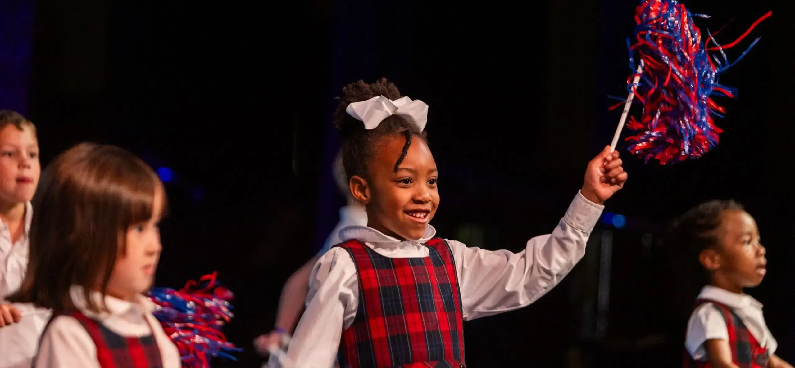 Child on stage waving pom-pom