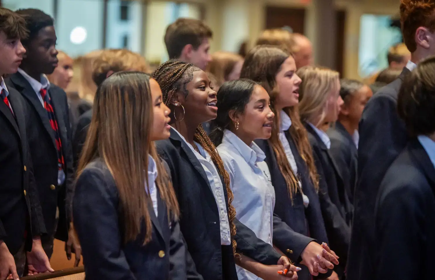 Students singing, hands linked