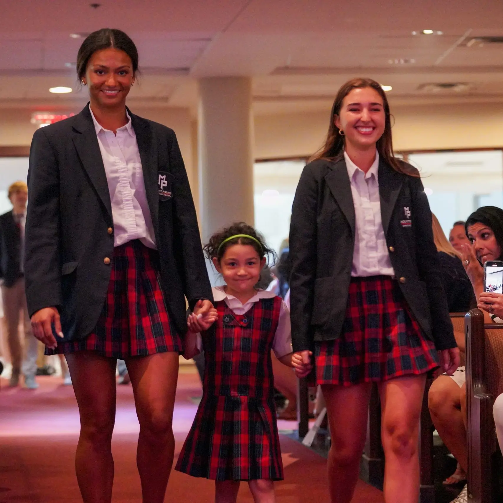 Two older girls holding a younger girl's hands