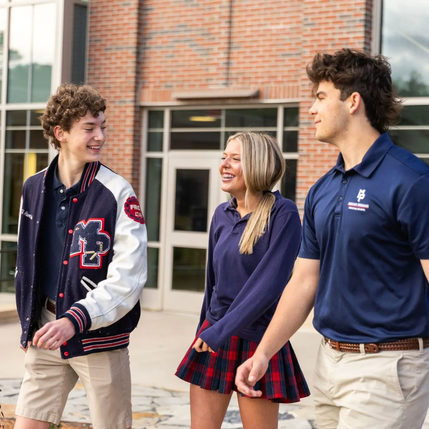 Three high school students walk together outside the school